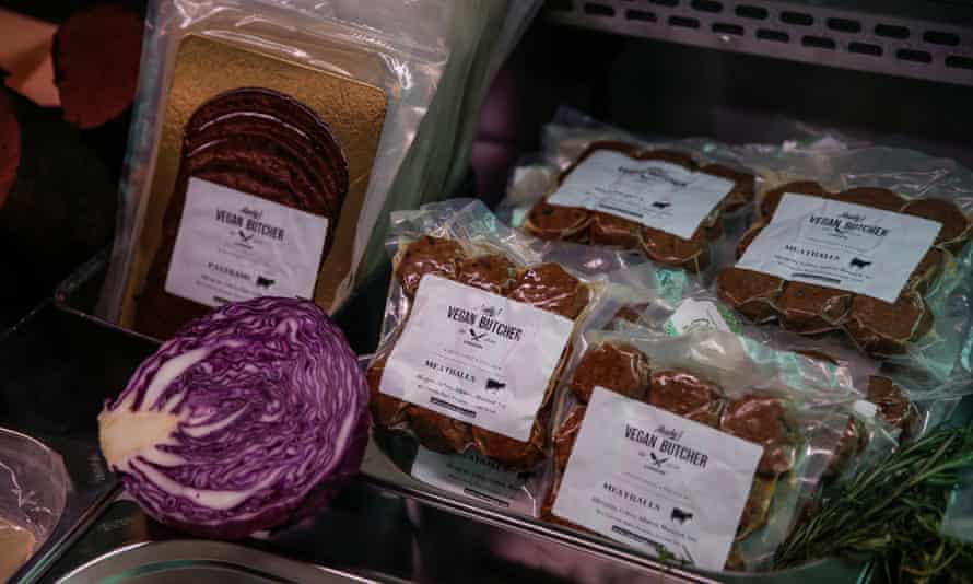 Close-up of a shelf of plastic-wrapped products including 'meatballs', with half a red cabbage placed as decoration