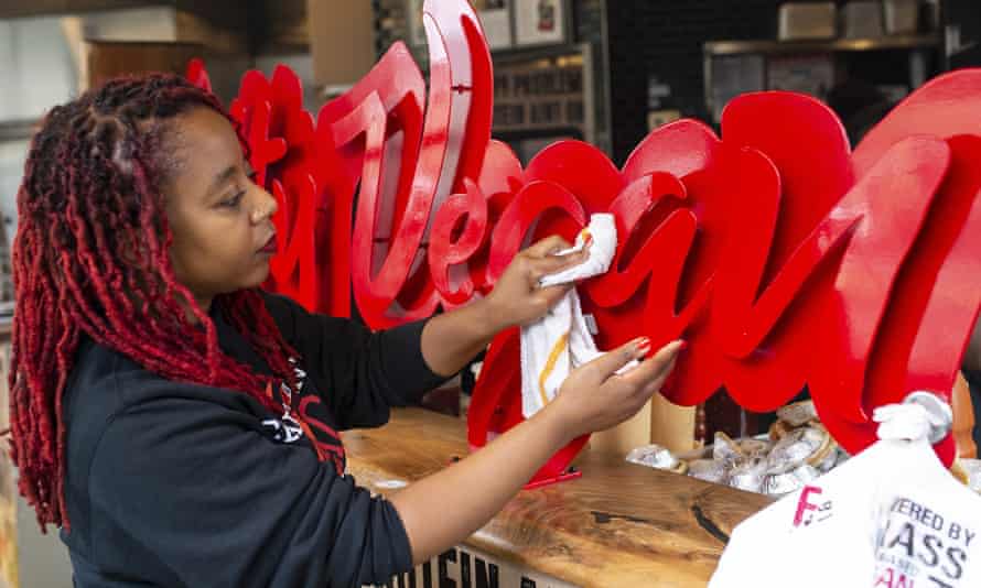 Aisha Pinky Cole, owner of Slutty Vegan restaurants and food trucks, wipes down a sign on her storefront in Atlanta.