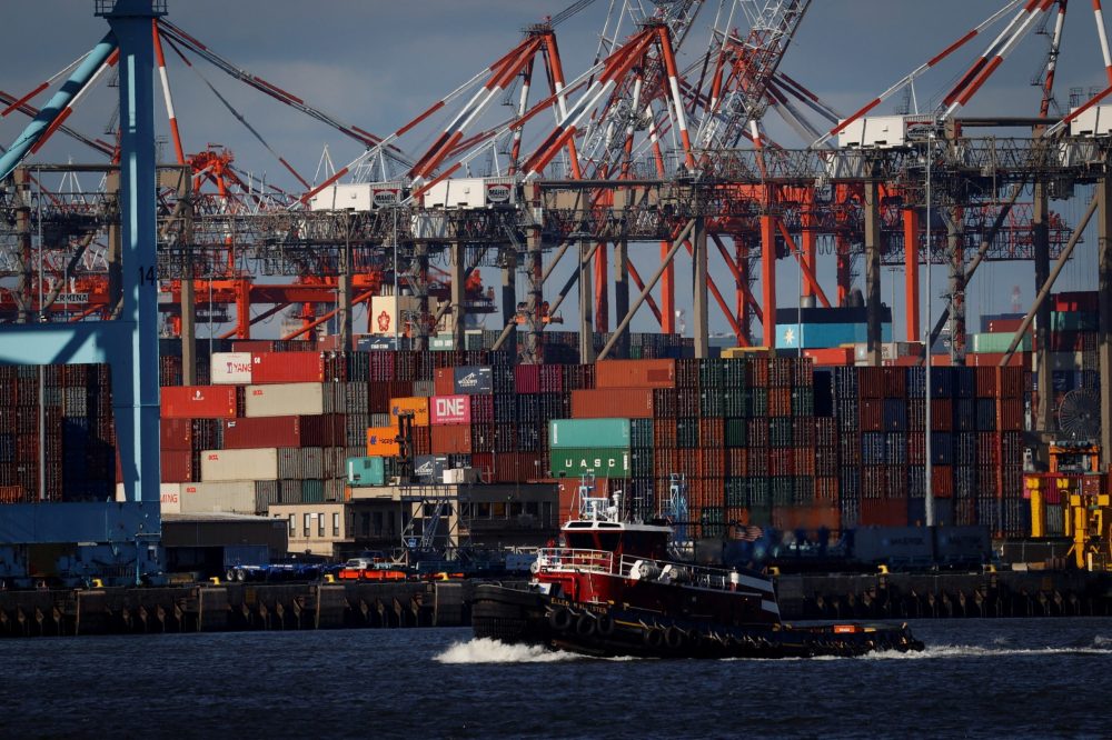 A tugboat passes shipping containers being unloaded and stacked on a pier at Port Newark, New Jersey, U.S., November 19, 2021.
 Photo: Reuters/Mike Segar/File
