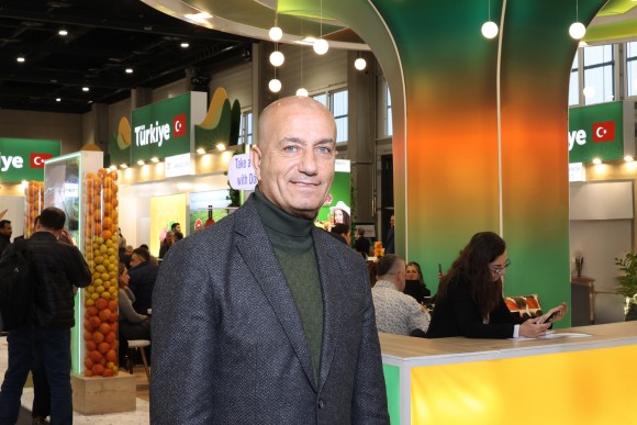 A man stands at a trade fair stand and looks friendly. 