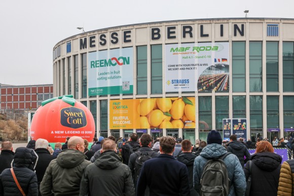 The entrance of Messe Nord can be seen with some banners and many people in front of it.