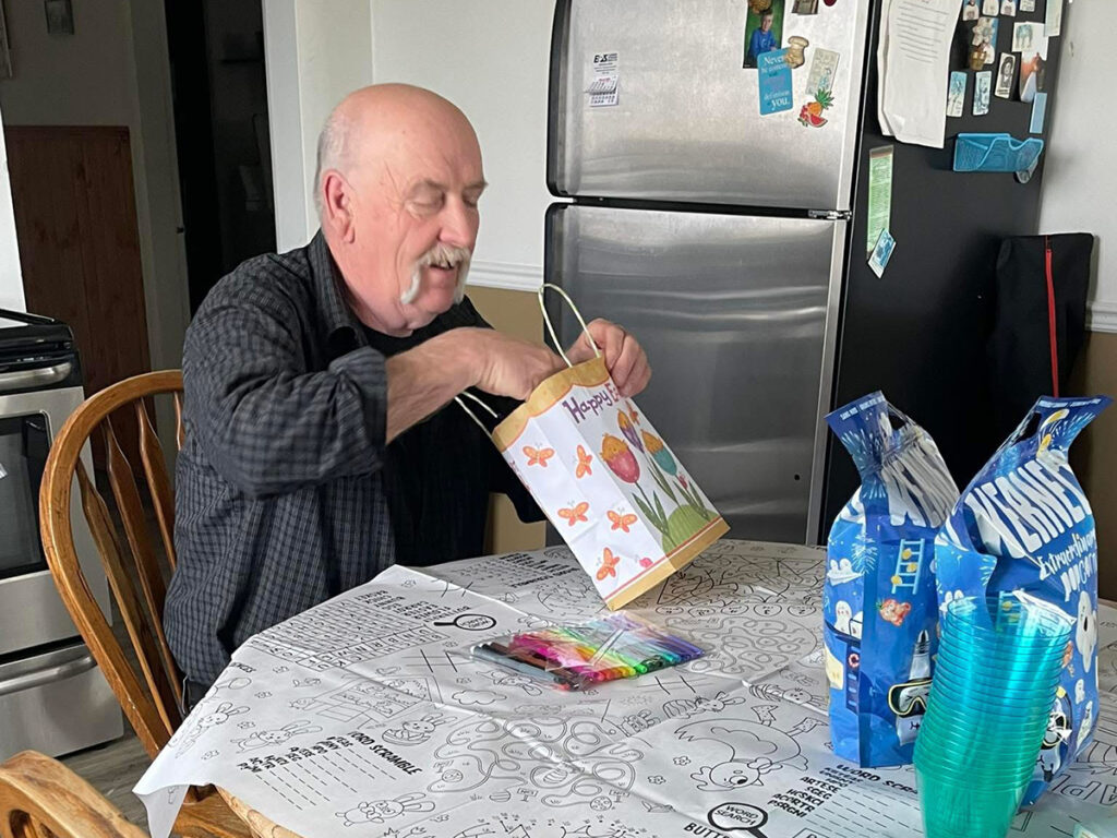 Henk Van Essen sits at his kitchen table looking at a gift bag with several other bags awaiting his attention.