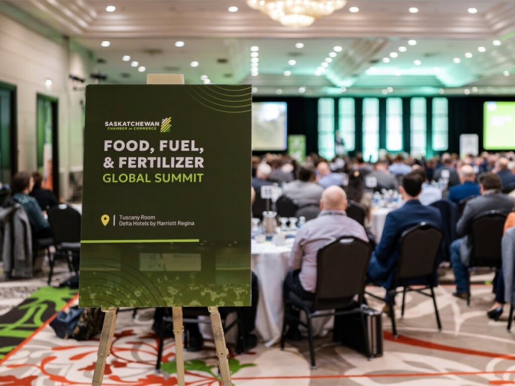A sign at the back of a meeting room filled with people promoting the Food, Fuel and Fertilizer summit.
