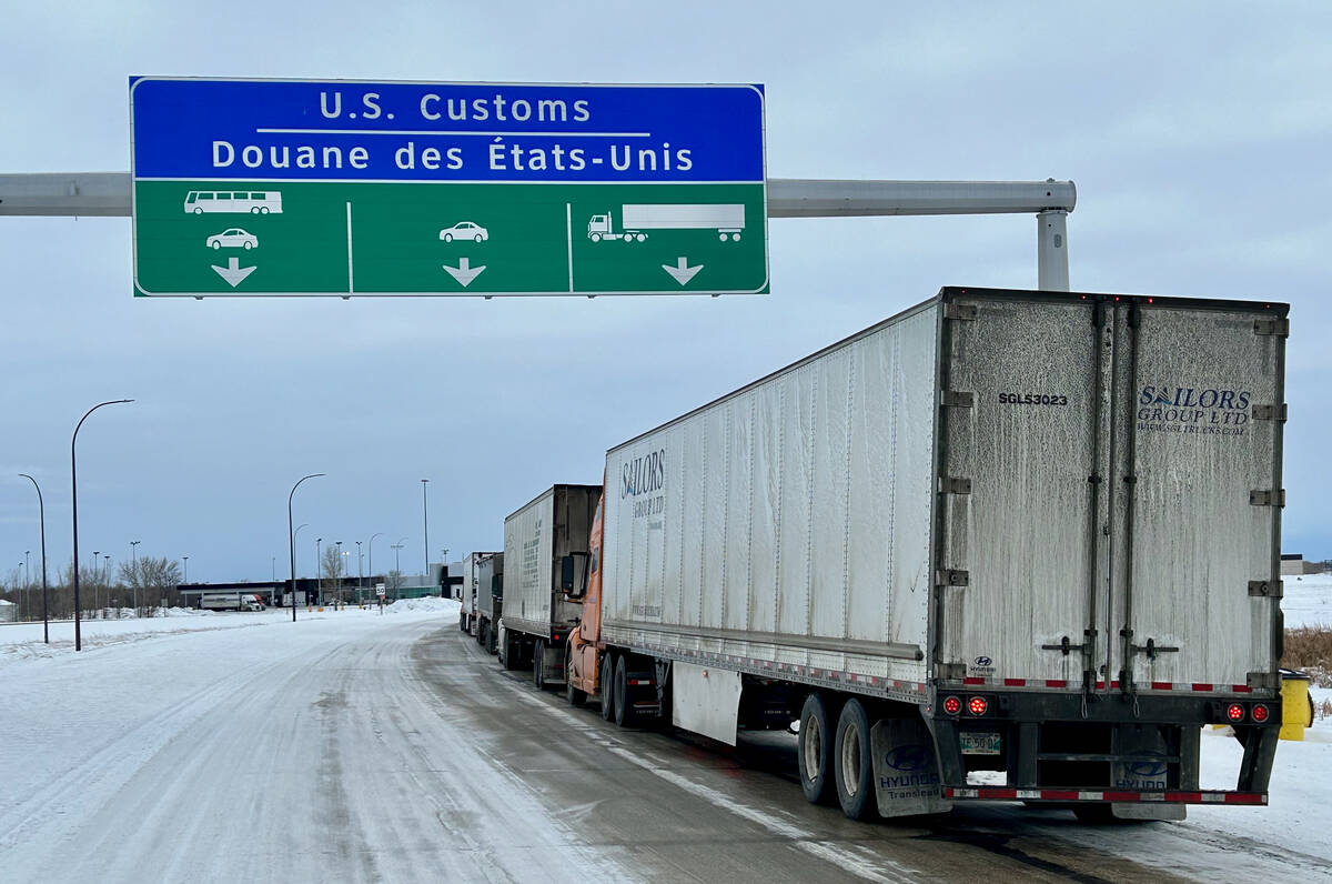 Trucks are lined up on a highway under as sign that reads, 