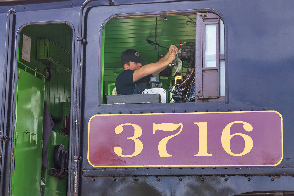 An engineer makes adjustments to Locomotive 3716, an old-fashioned steam locomotive that's part of the Kettle Valley Railway.