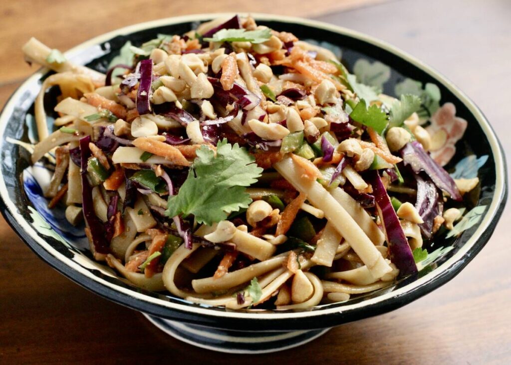 A pasta salad sits in a bowl on a table.