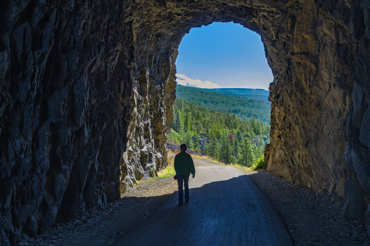 A tourist walks through the Little Tunnel on the Kettle Valley Railway Trail.