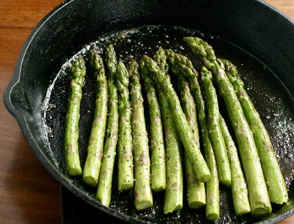 Cooked asparagus sitting in a cast iron skillet.