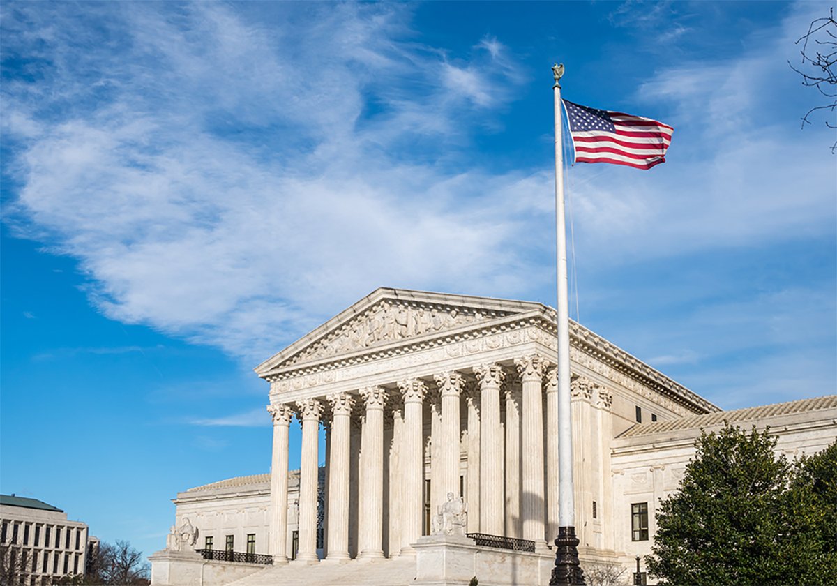 A stock image of the U.S. Supreme Court building in Washington, D.C., with an American flag flying in the foreground.