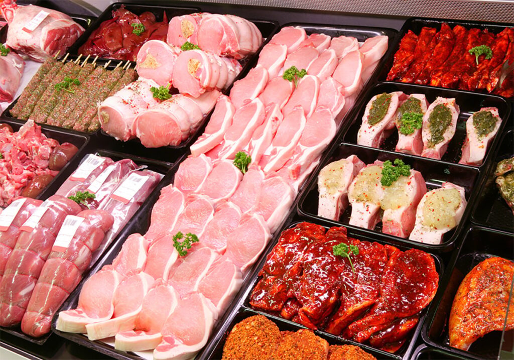 Various pork meat products are on display in a butcher shop.