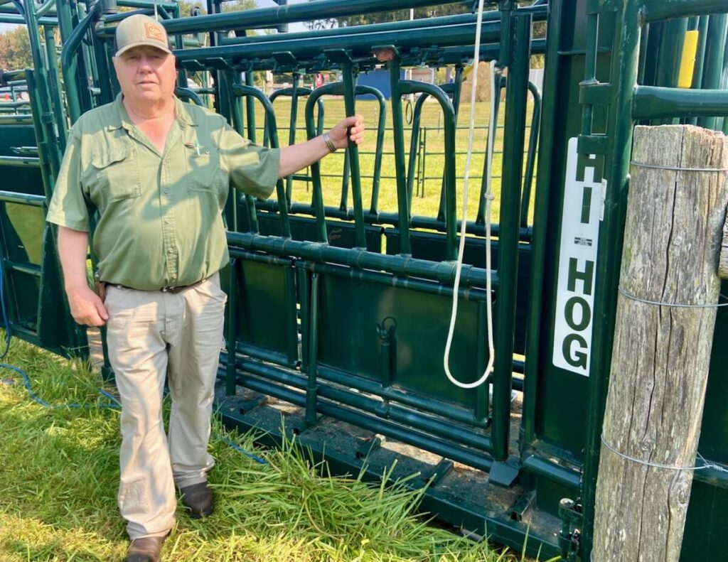 Myron Wigness stands with a Hi-Hog cattle squeeze unit.