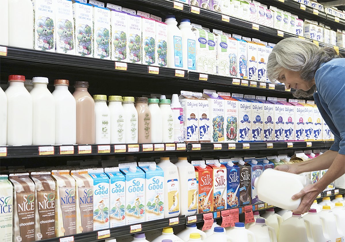 A woman looks at dairy items in a grocery store.