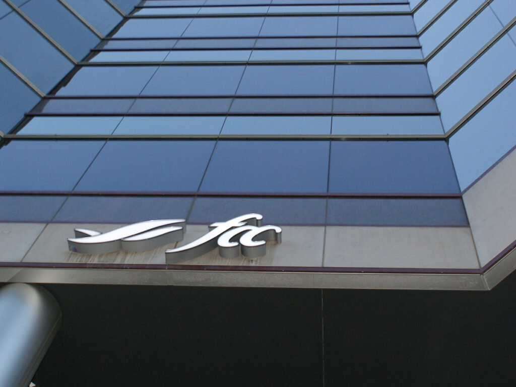 Looking upward at a tall, blue building with an Farm Credit Canada (FCC) logo on it.