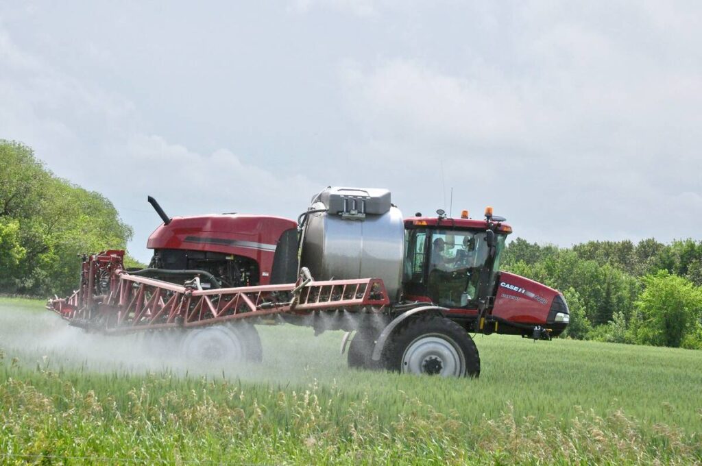 A modern high-clearance sprayer is spraying a recently-emerged crop.