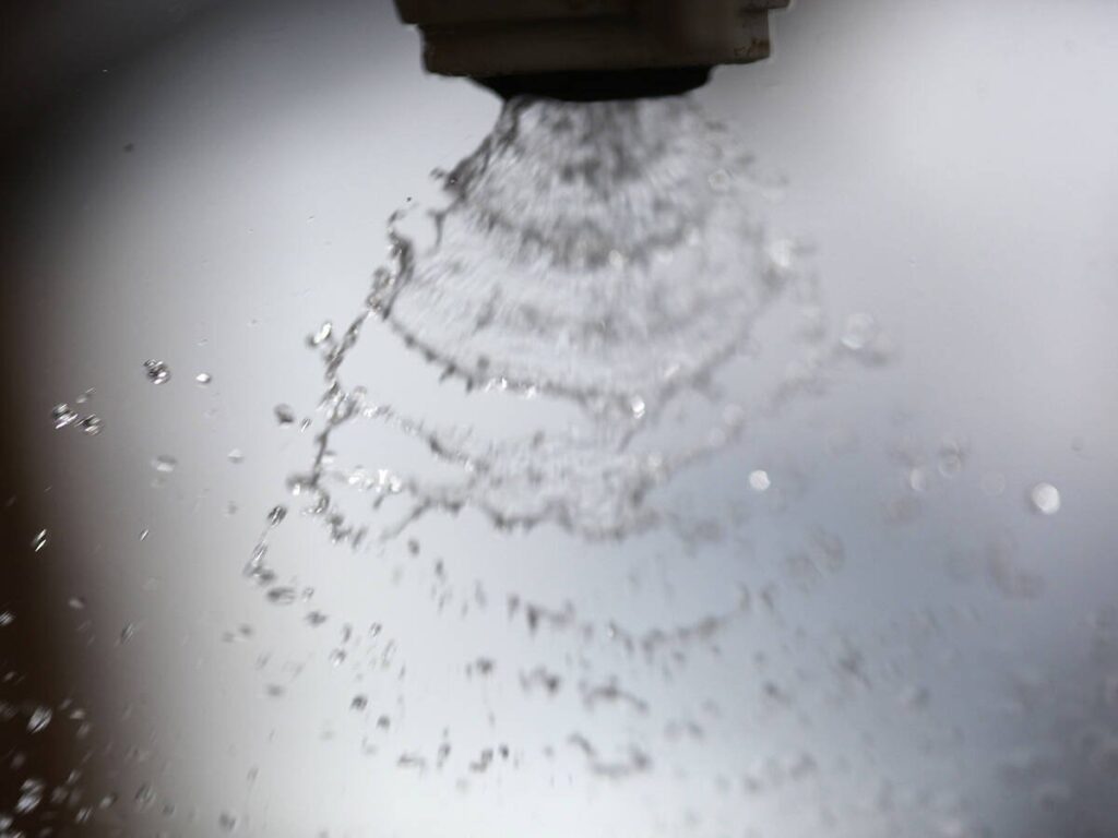 An extreme close-up of the fan-like pattern created by droplets leaving the nozzle of a sprayer.