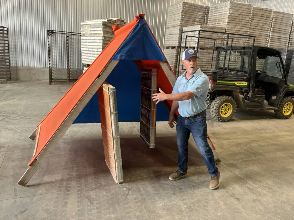 Cory Nelson, a member of the Palliser Triangle Marketing Group, stands next to one of the tents he sets up in seed canola and alfalfa fields in southern Alberta to manage leafcutter bee colonies for pollination services.