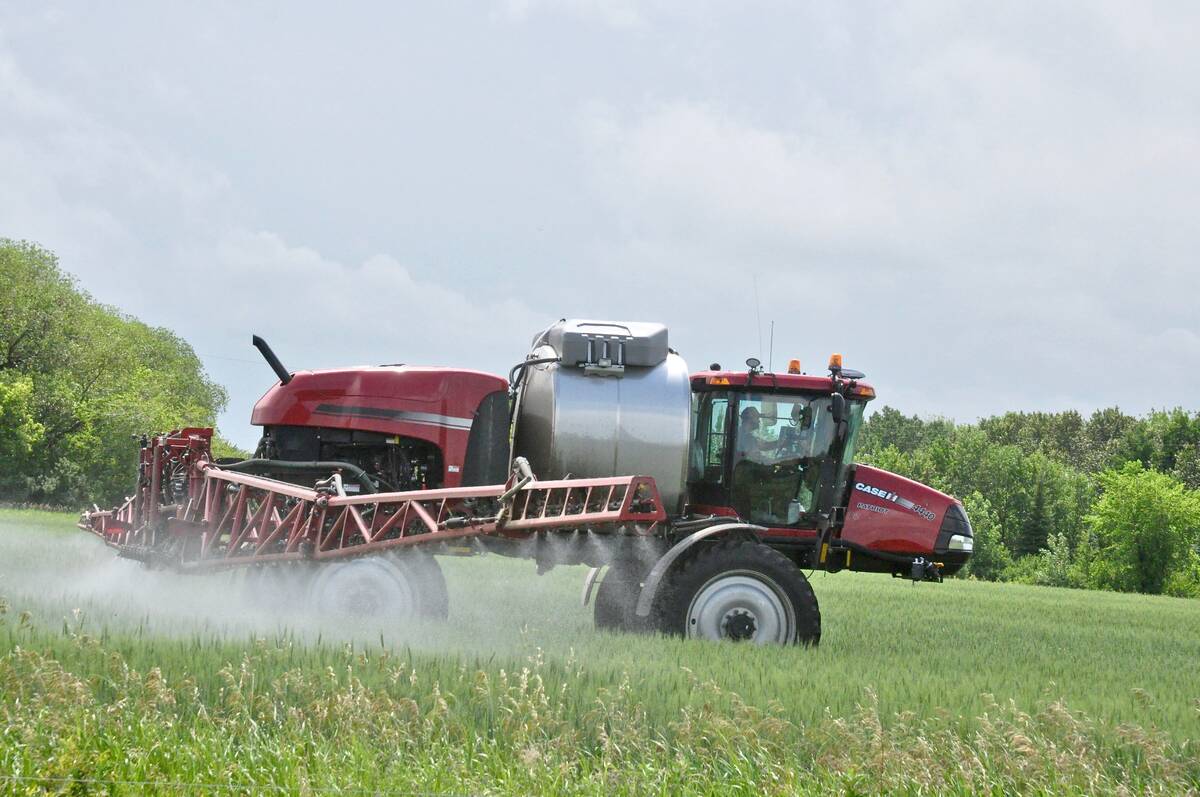 A modern high-clearance sprayer is spraying a recently-emerged crop.