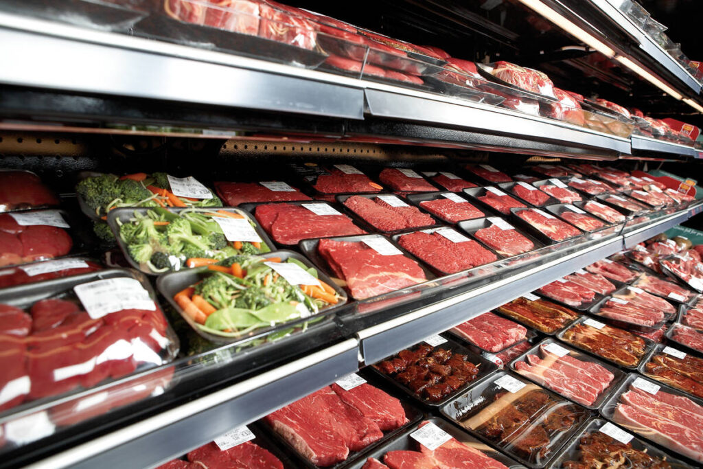 Various cuts of beef on display in the meat section of a grocery store.
