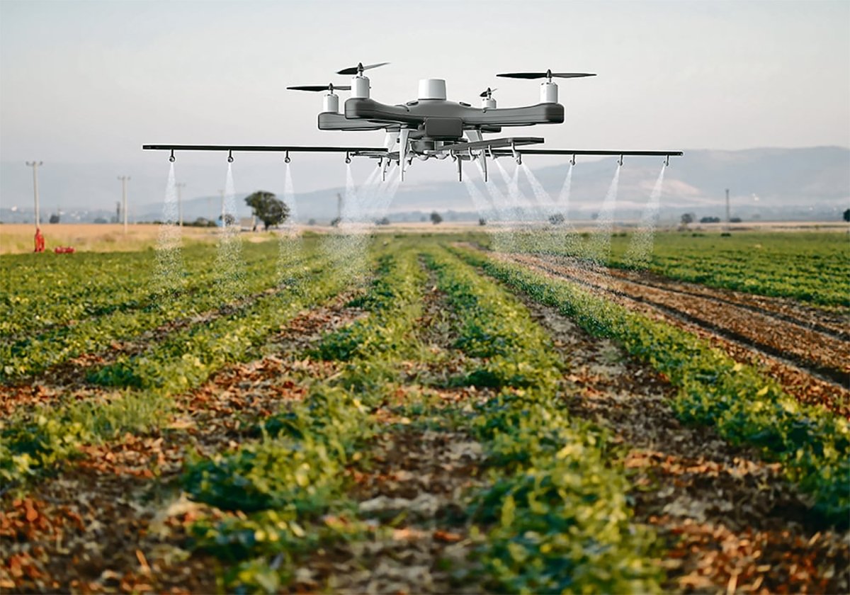 A large sprayer drone hovers over a crop while a large boom attached to it sends spray downward.