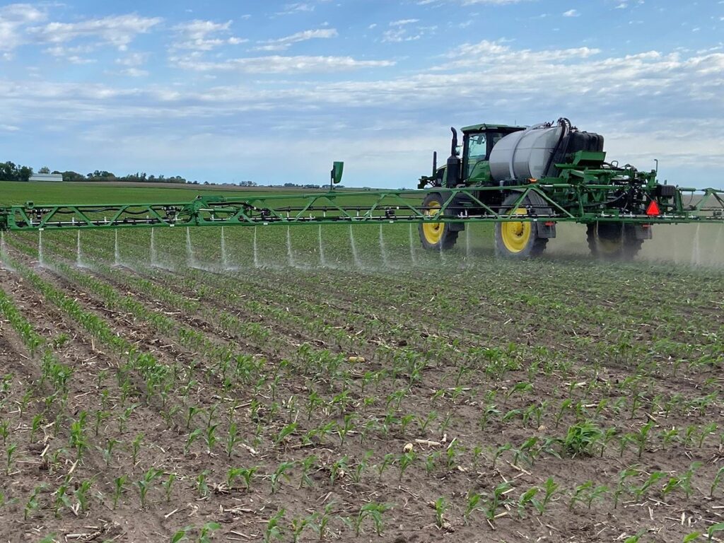 A ground spray rig applies nematodes to a corn field.
