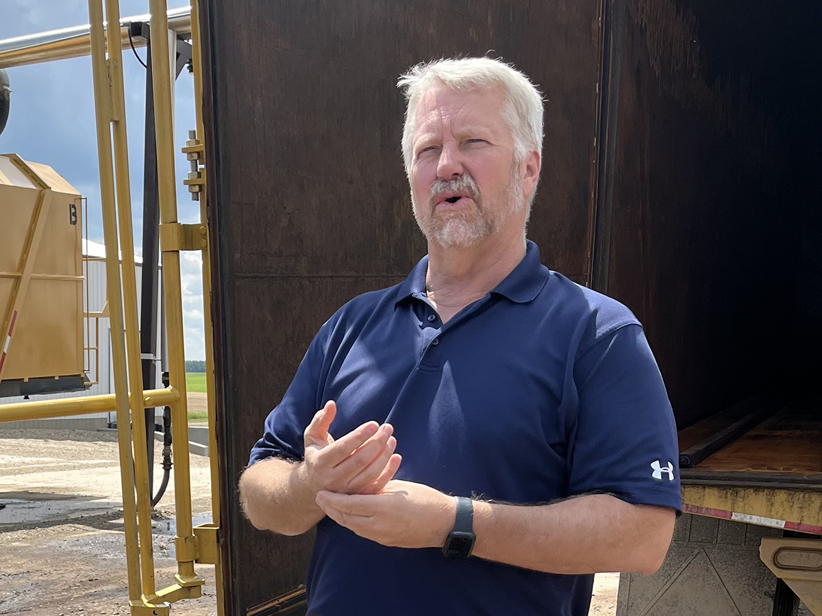 Quattro Ventures' chief executive officer John Van Tryp speaks while standing on the ground in front of the open doors of an empty semi trailer.