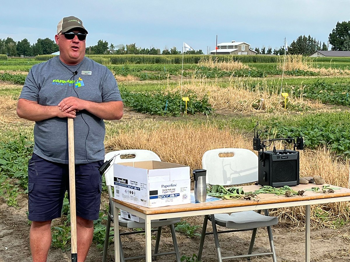 Kevin Coles, executive director of Farming Smarter, stands beside a table leaning on a shovel and talking about cover crop benefits at a recent field school.