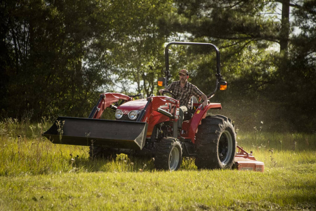 Promotional image of a man wearing a ball cap mowing using an Agco 2700E Series utility tractor.