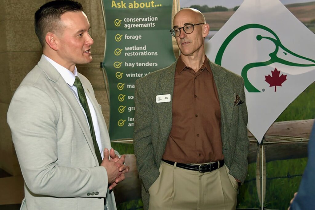 Ken Gross, right, listens to Manitoba environment minister Mike Moyes inside the Manitoba legislature in Winnipeg.