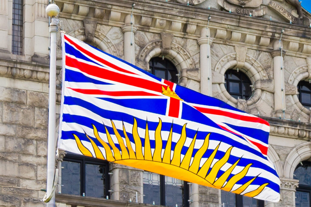 A photo of the flag of British Columbia flying in front of the B.C. legislature in Victoria.