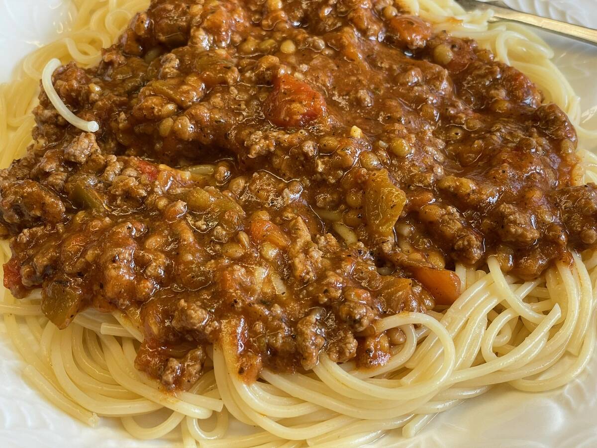 A plate with pasta topped with a hearty meat sauce on it.
