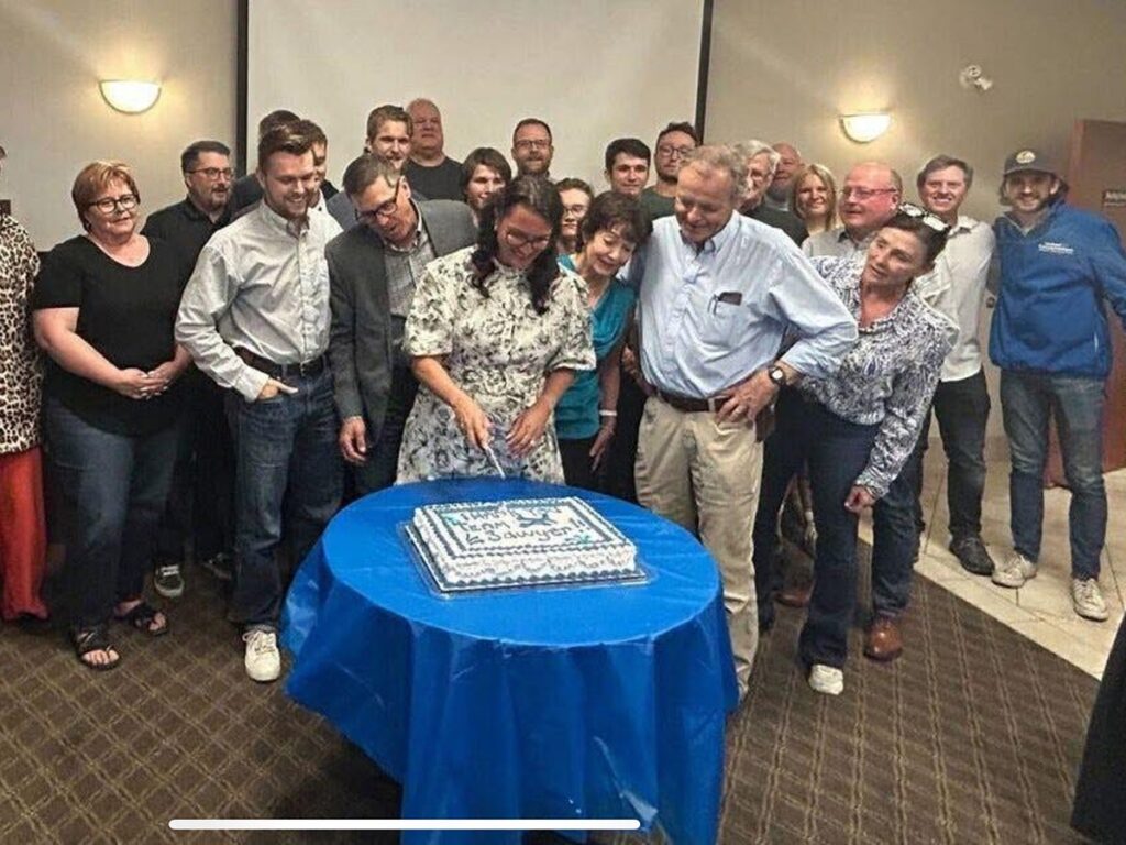 A woman cuts a cake with others standing nearby in a celebration.