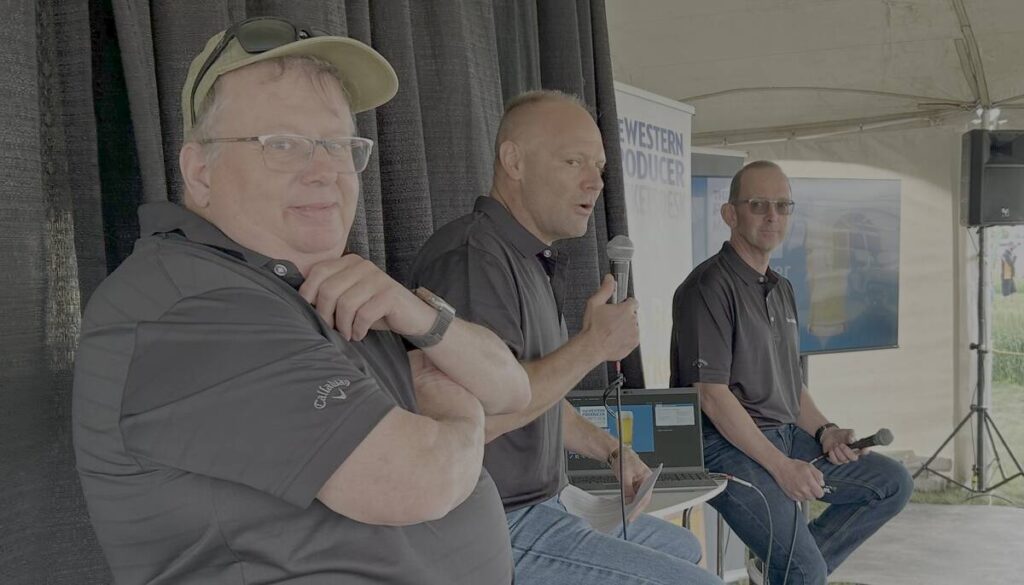 Bruce Burnett, left, Jerry Klassen and Ranulf Glanville talk markets at the Ag in Motion farm show near Langham, Sask.