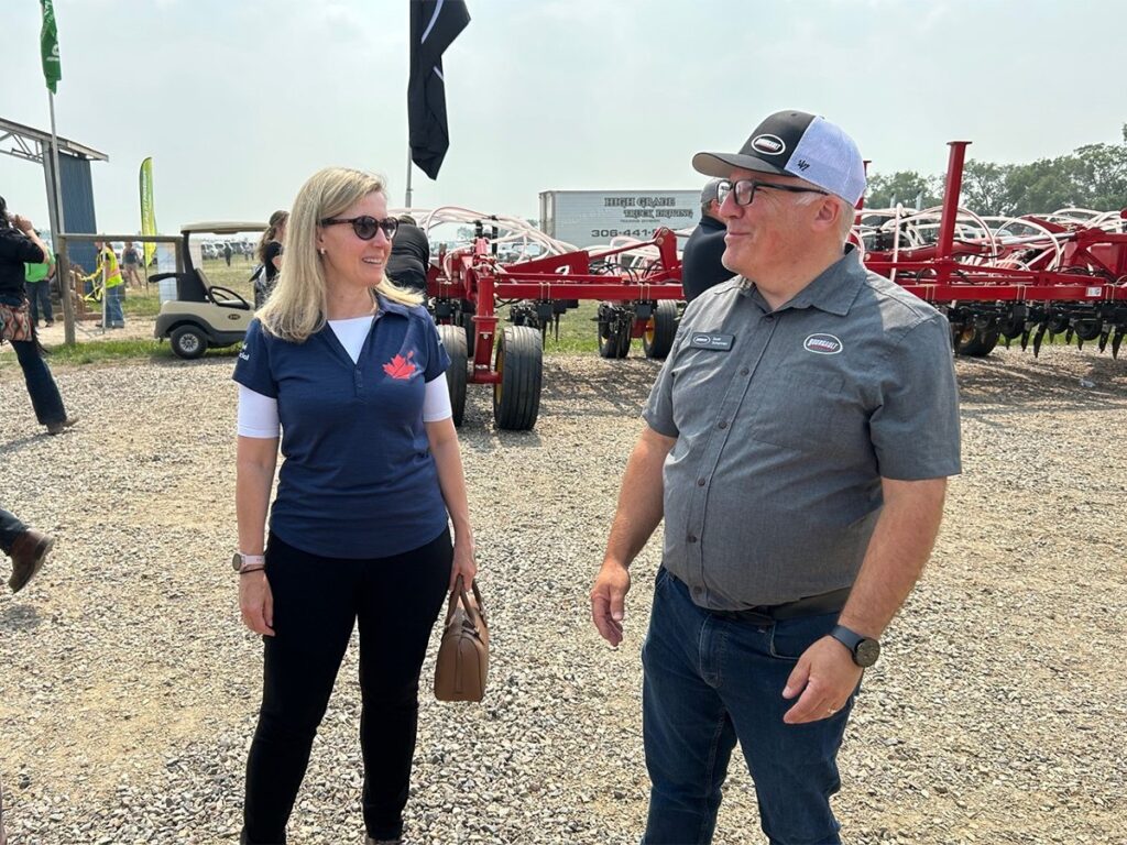 Canadian Chief Trade Commissioner Sara Wilshaw speaks with Scott Scherman of Bourgault industries at Ag In Motion 2025, near Langham, Sask.