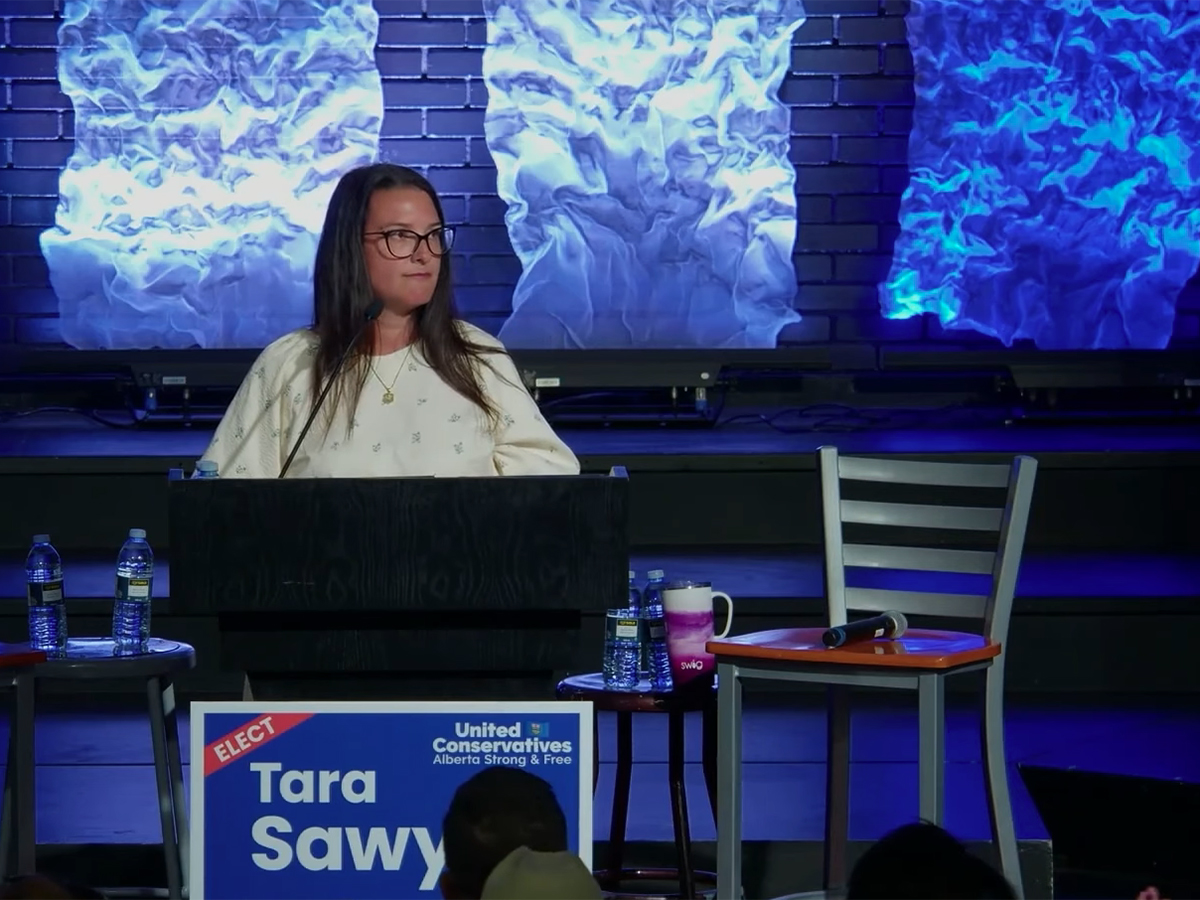 United Conservative Party candidate Tara Sawyer speaks to a room of people from a lecturn on the campaign trail prior to the byelection she would go on to win on June 23, 2025.