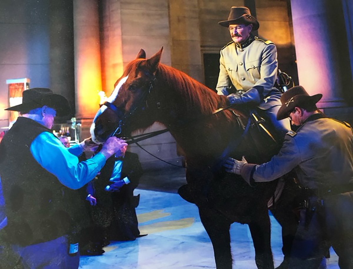 2025 Alberta Order of Excellence inductee John Scotts calms a horse with Robin Williams sitting on it on the set of Night at the Museum.