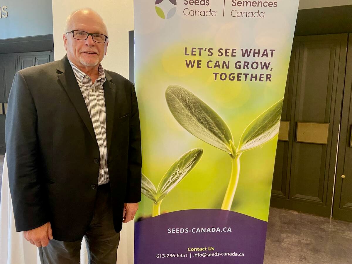 Barry Senft, CEO of Seeds Canada, poses next to a Seeds Canada banner.
