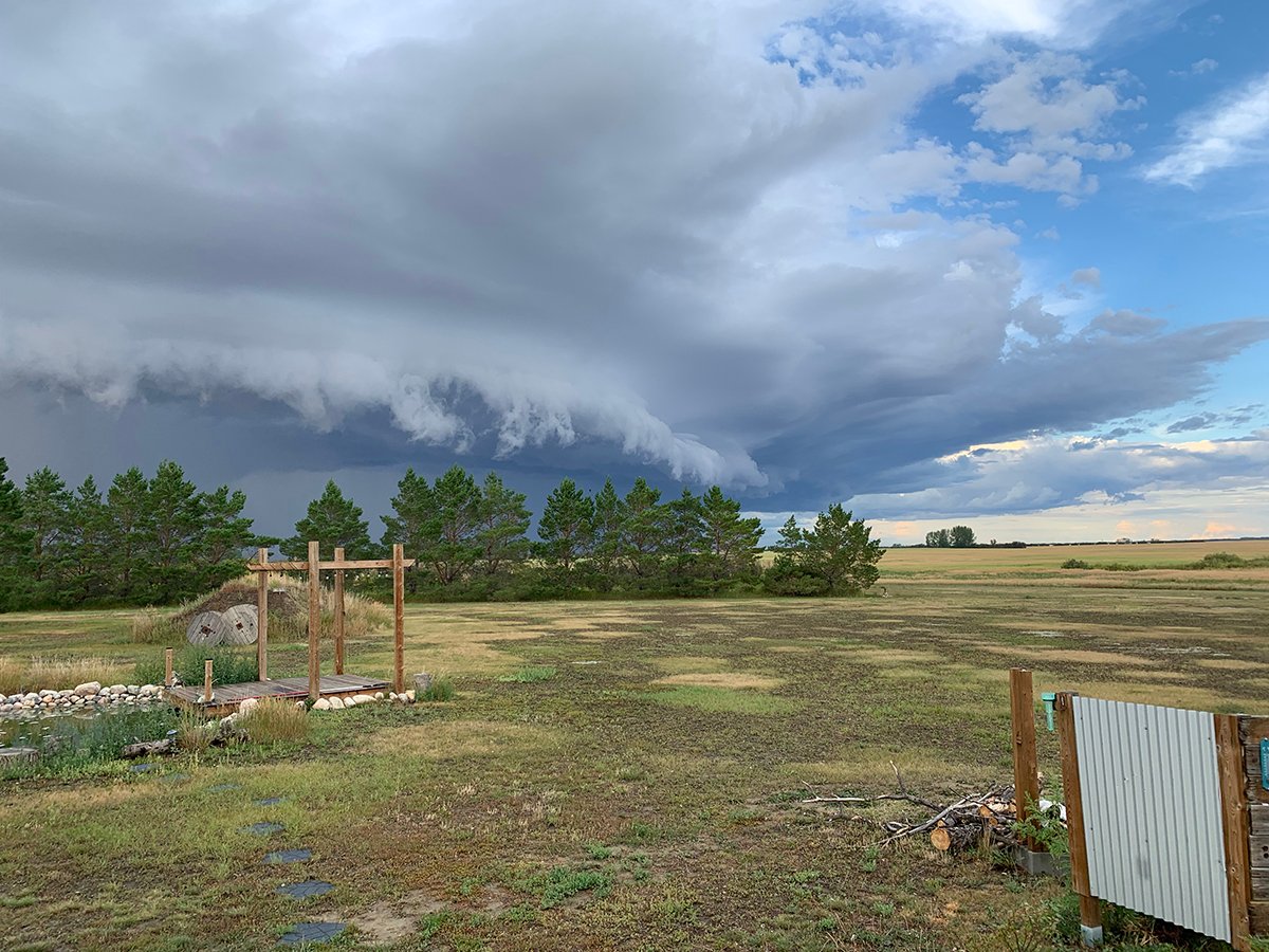 A clear view of a storm front as the cloud moves in over a prairie yard site.