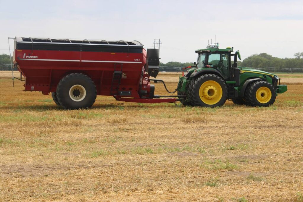 A photo of an autonomous tractor pulling a grain cart in a field.