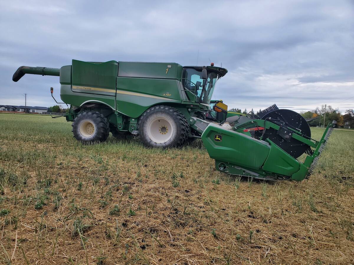 A combine is parked in a field under a cloudy sky.