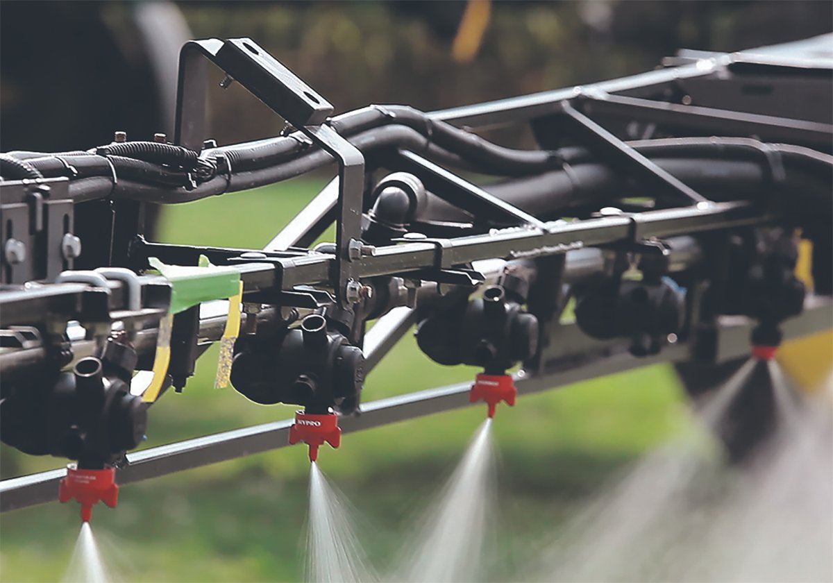 Liquid flows from the nozzles on a high clearance sprayer's boom.