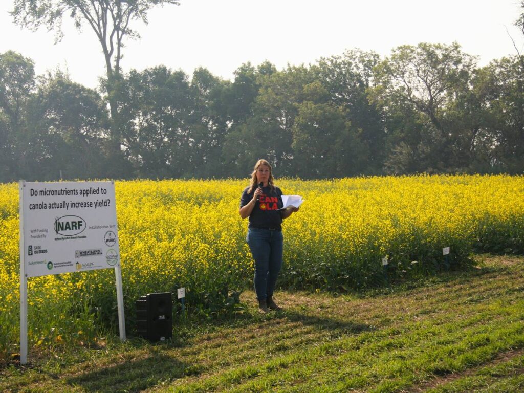 Kaeley Kindrachuk of SaskOilseeds stands in front of some canola trial plots at a Northeast Agriculture Research Foundation field day near Melfort, Saskatchewan.