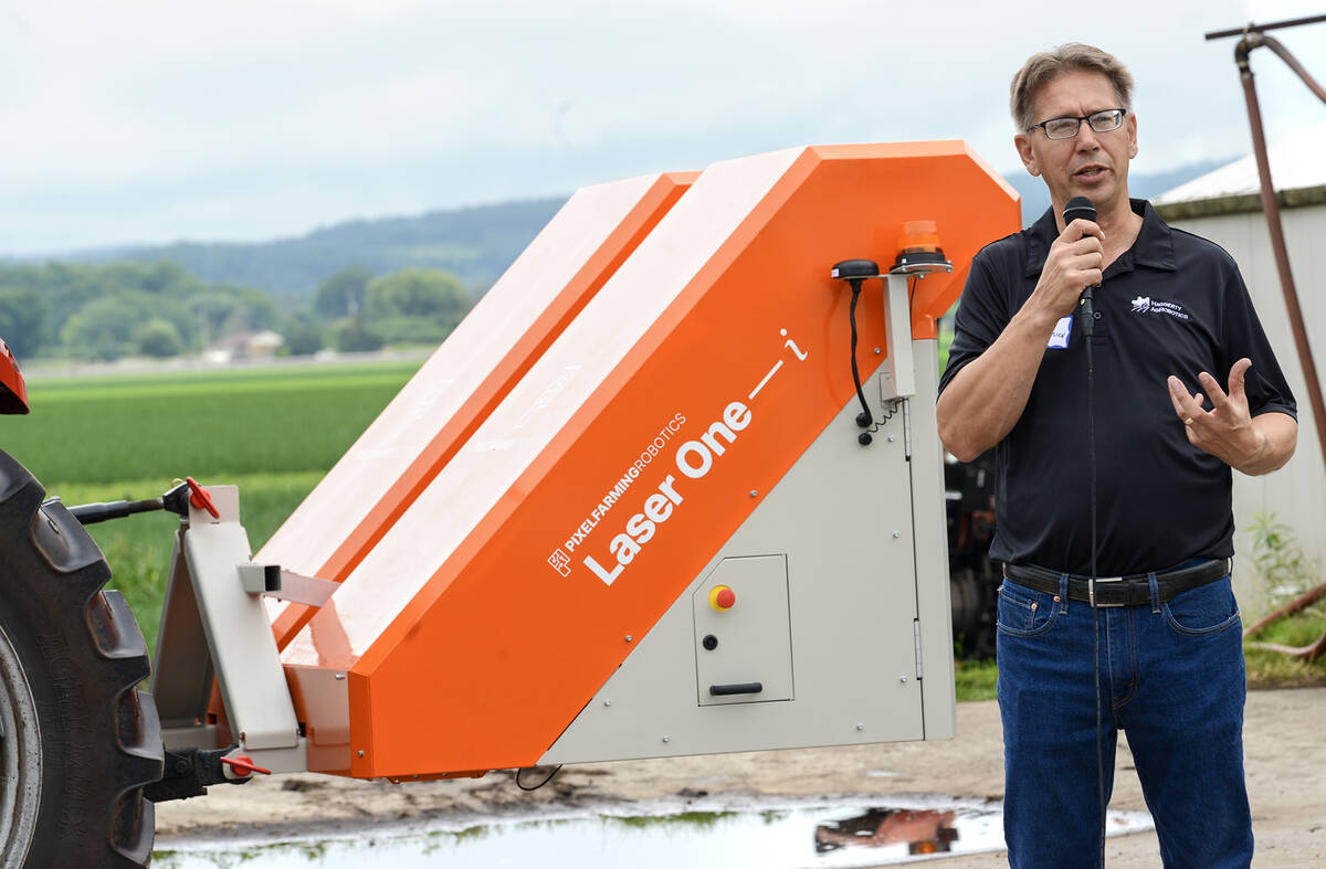 Chuck Baresich of Haggerty AgRobotics, speaks into a microphone in front of the Pixelfarming Laser One–i prototype autonomous weeding machine.