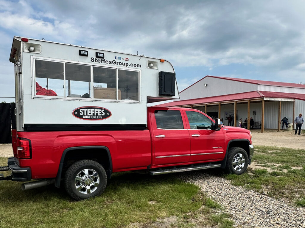 A red half-ton truck with a modified camper in the box and 