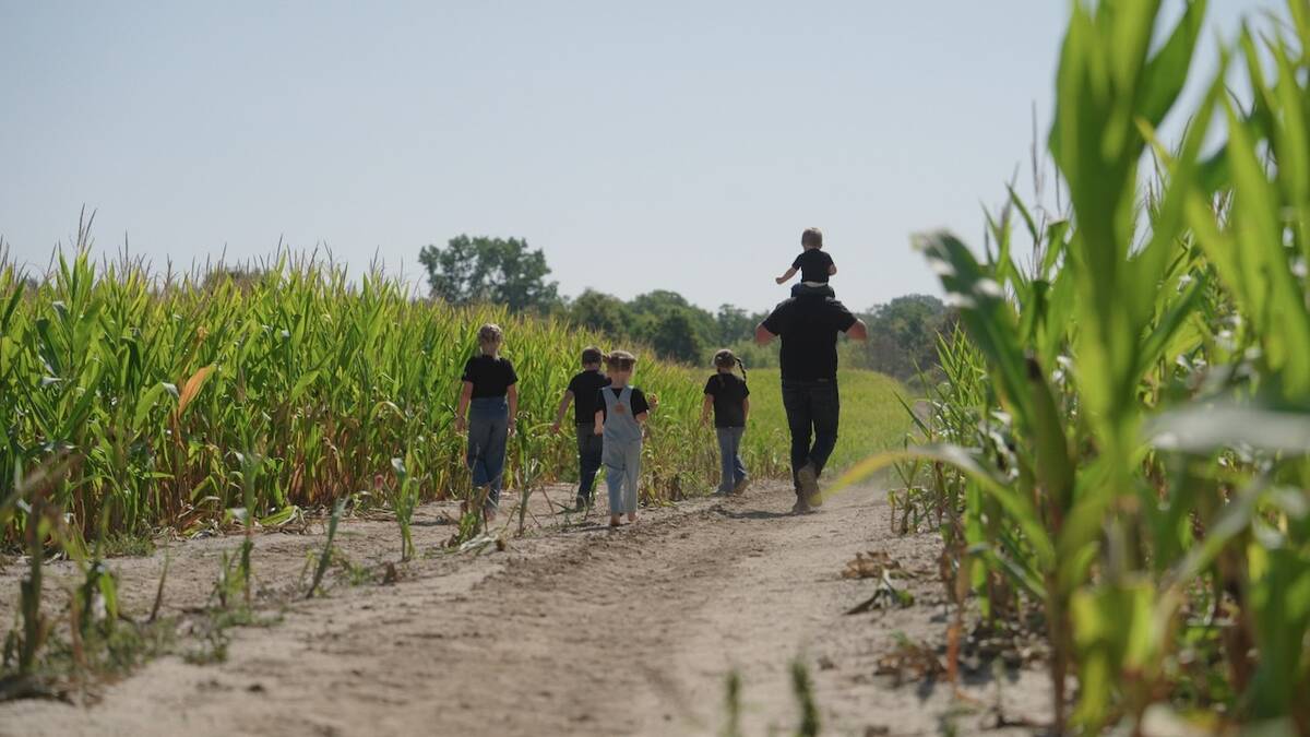 Tobias Burgin and his family walk along a corn field on their farm. Photo: Courtesy CANZA