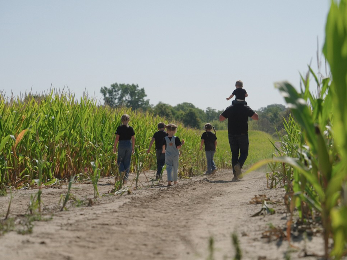 Tobias Burgin and his family walk along a corn field on their farm.