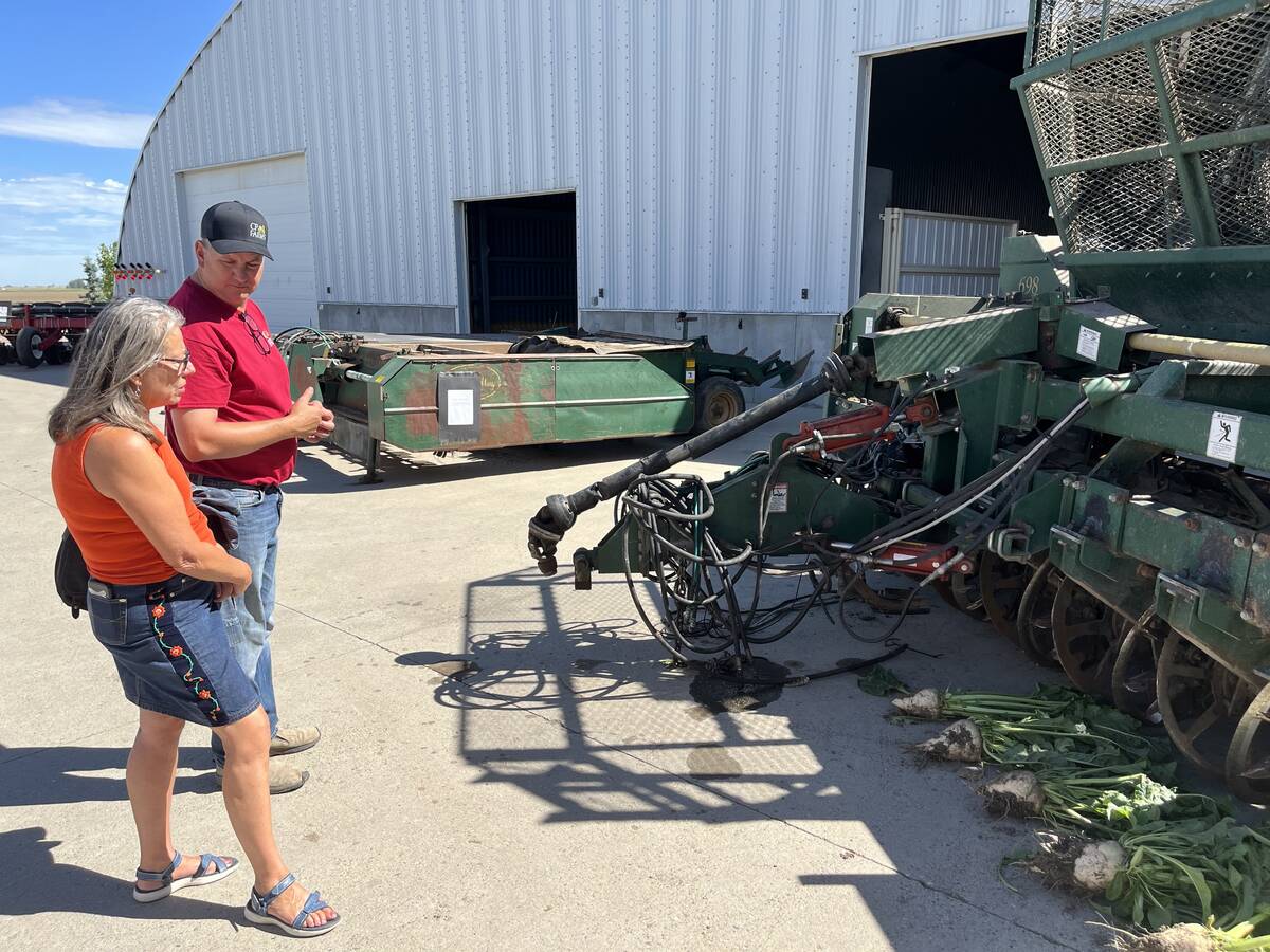 A man and a woman stand in front of a sugar-beet harvesting machine that was on display during a recent Open Farm Days tour.