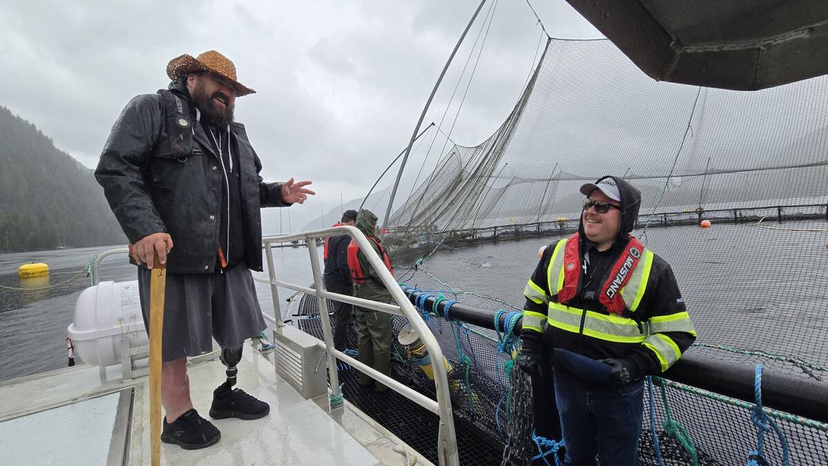 Dallas Smith, left, talks to a Mowi salmon farm worker on a fish farm in Kitasoo Xai’xais territory.