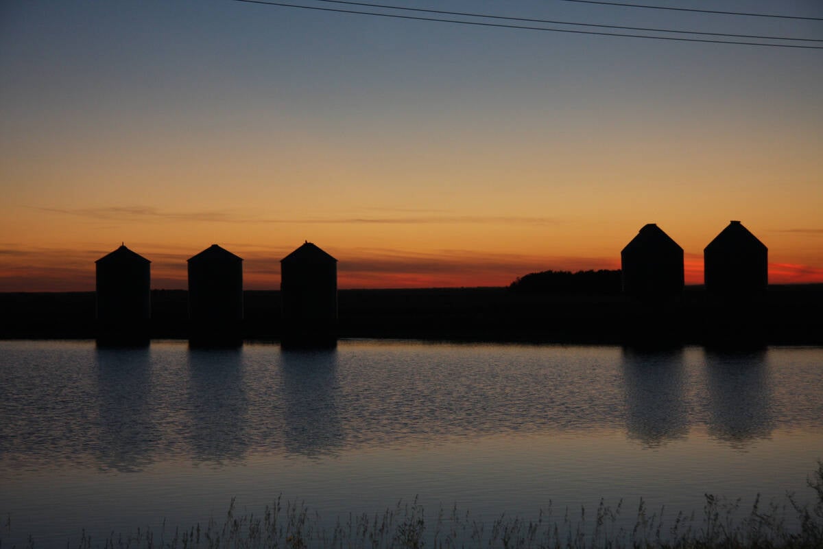 Grain bins are silhouetted at sunset off Highway 16 north of Dafoe, Saskatchewan.