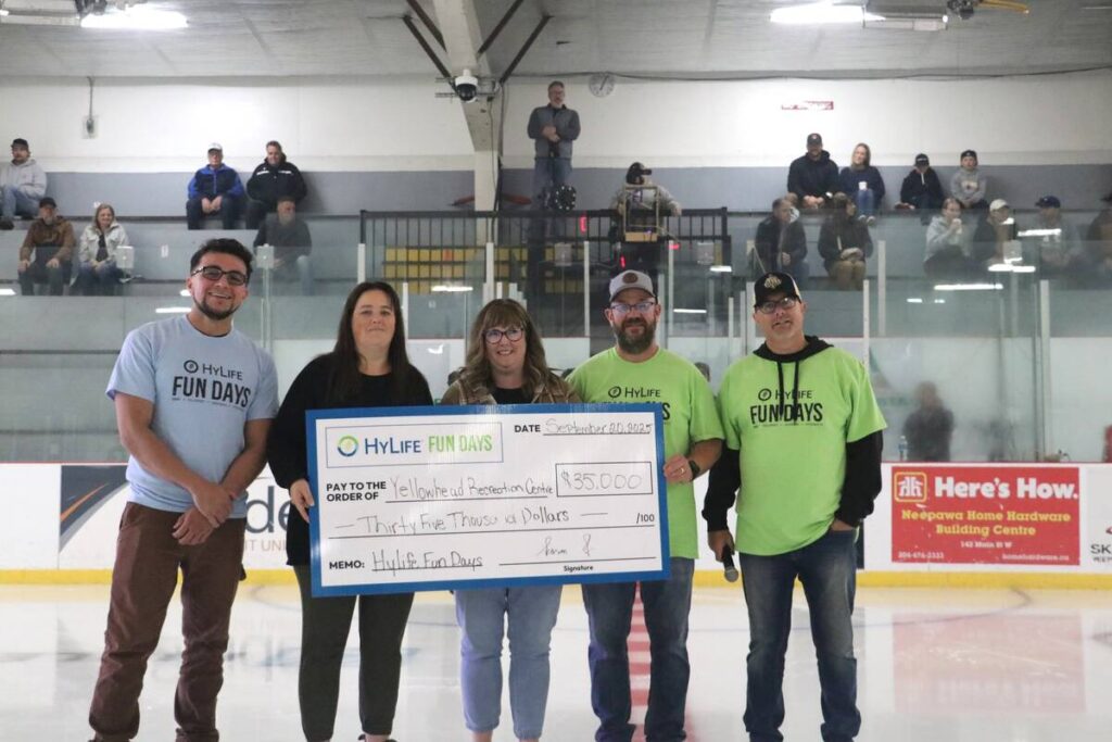 Five people stand at centre ice in a hockey arena holding a large cheque for $35,000 from 
