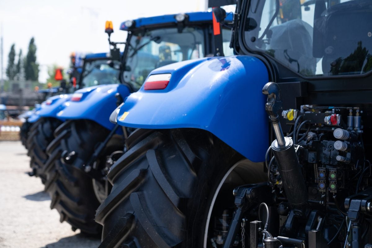 Close up on the fender of a blue tractor in a line of blue tractors.